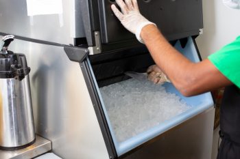A View Of An Employee Scooping Ice Out Of An Ice Machine, In A Restaurant Setting