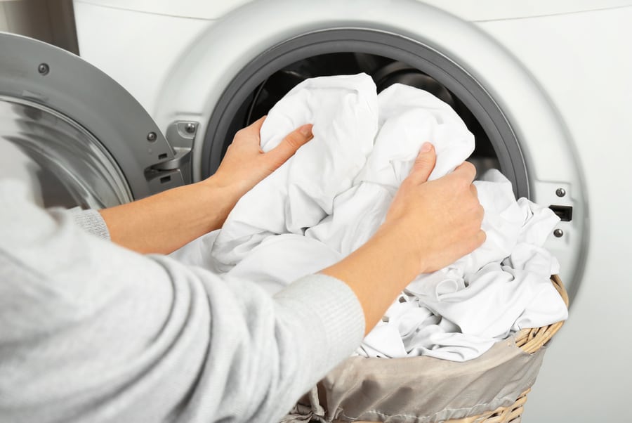 A Woman Getting The Clean Clothes Out Of The Washing Machine