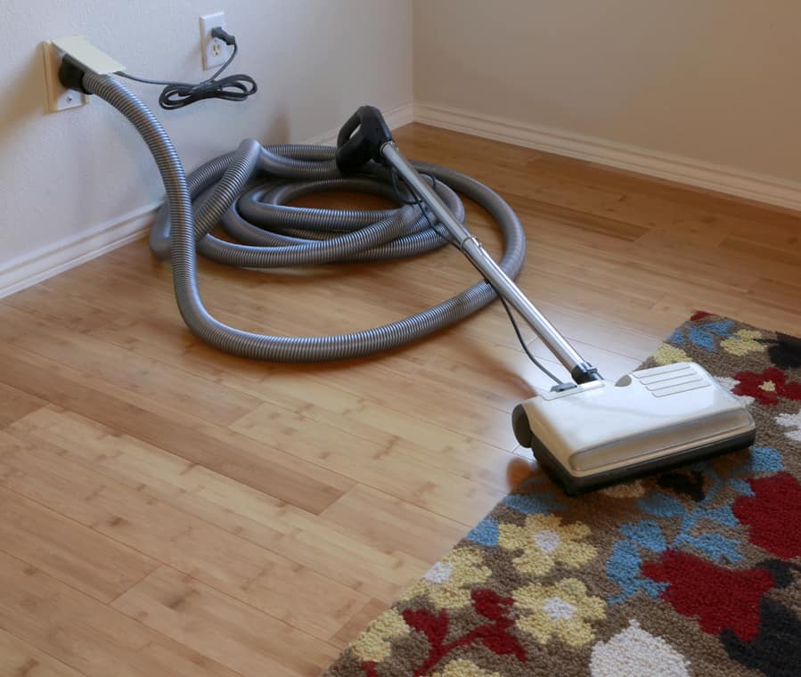 Beautiful Bamboo Hardwood Floor And Wool Rug With A Central Vacuum Cleaner Attached To The Wall