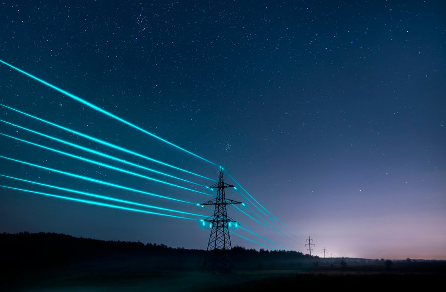Electricity Transmission Towers With Glowing Wires Against The Starry Sky