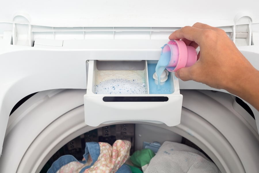 Hand Holding Fabric Softener In Washing Machine.