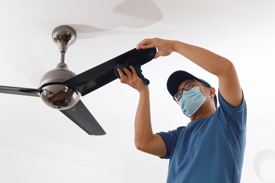 Male Cleaning Ceiling Fan At Home.
