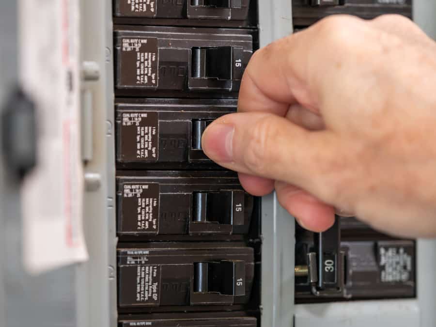 Male Electrician Turning Off Power For Electrical Outlet At Circuit Breaker Box