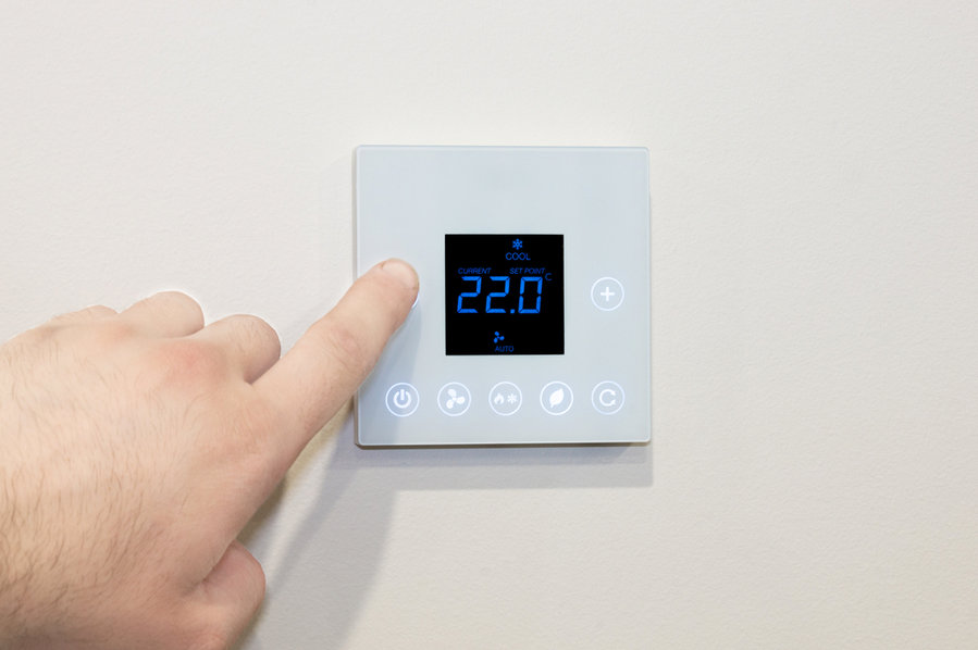 Man Adjusting A Thermostat