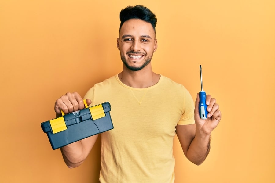 Man Holding A Screwdriver And A Cleaning Kit