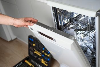 Man Repairing A Dishwasher With Tools