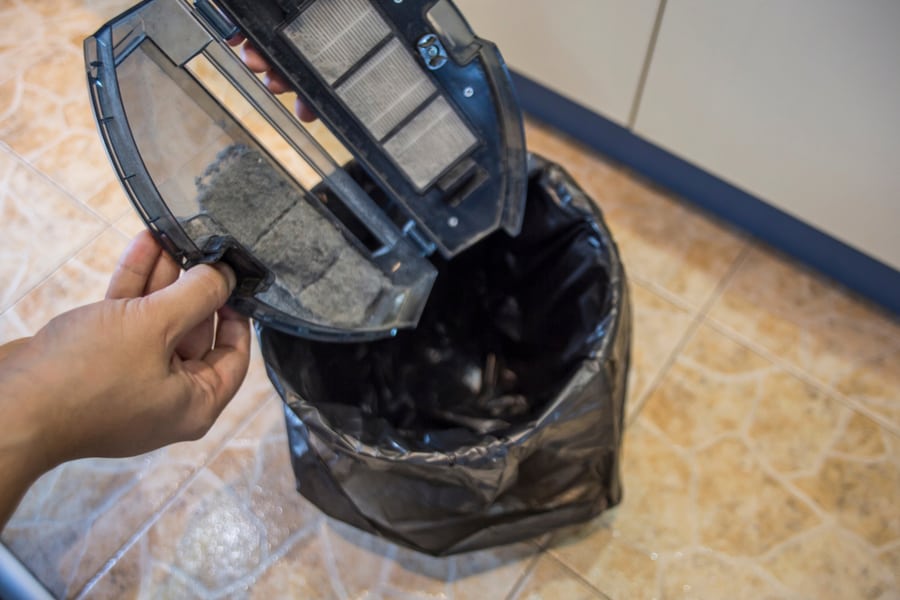 Person Cleaning The Dust Bin Of A Robot Vacuum Cleander.