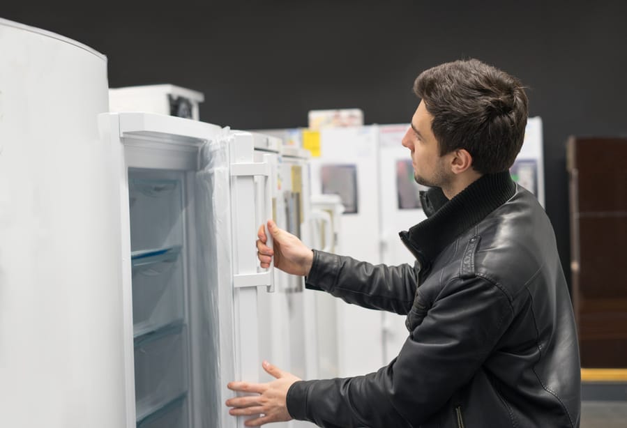 Portrait Of Male Customer Choosing Refrigerator In Supermarket Store