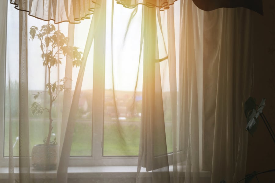 Rays Of Sunlight Through Transparent Curtain Of Open Window Of Room Shine