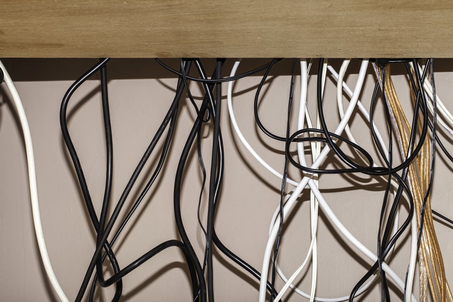 Untidy Cables Hanging Behind A Computer Desk