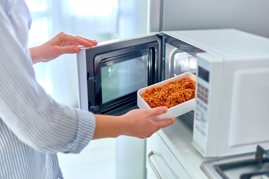 Woman About To Warm Food Using Microwave Oven