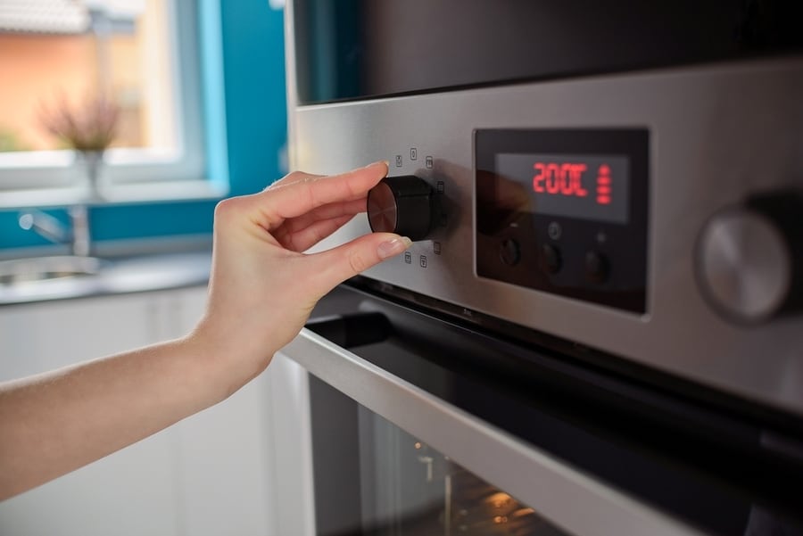 Woman Regulates The Temperature Of The Oven