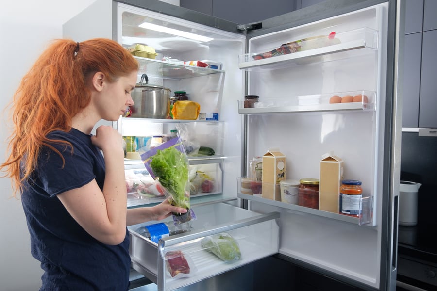Woman Standing At The Open Refrigerator With Fruits
