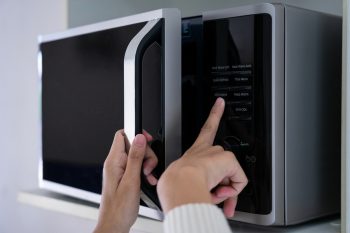 Womans Hands Closing Microwave Oven