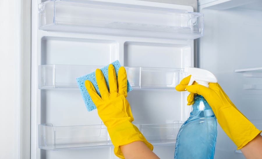 Woman's Hands In A Yellow Rubber Protective Glove And A Blue Sponge Washes, Cleans Refrigerator Shelves.