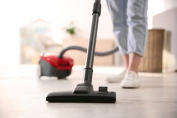 Young Woman Using Vacuum Cleaner At Home