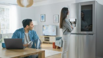 A Couple Looking At Their Newly-Bought Smart Fridge