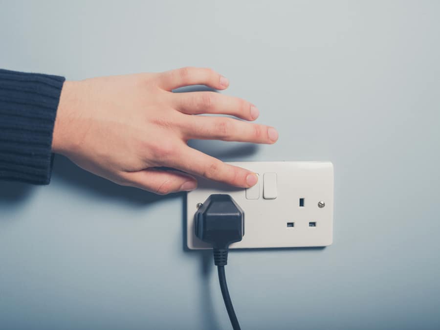 A Male Hand Is Pushing A Switch On A Wall Socket