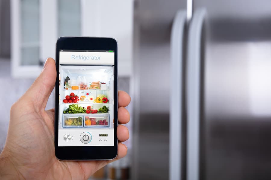 A Man Tracking The Food On The Fridge Through His Phone