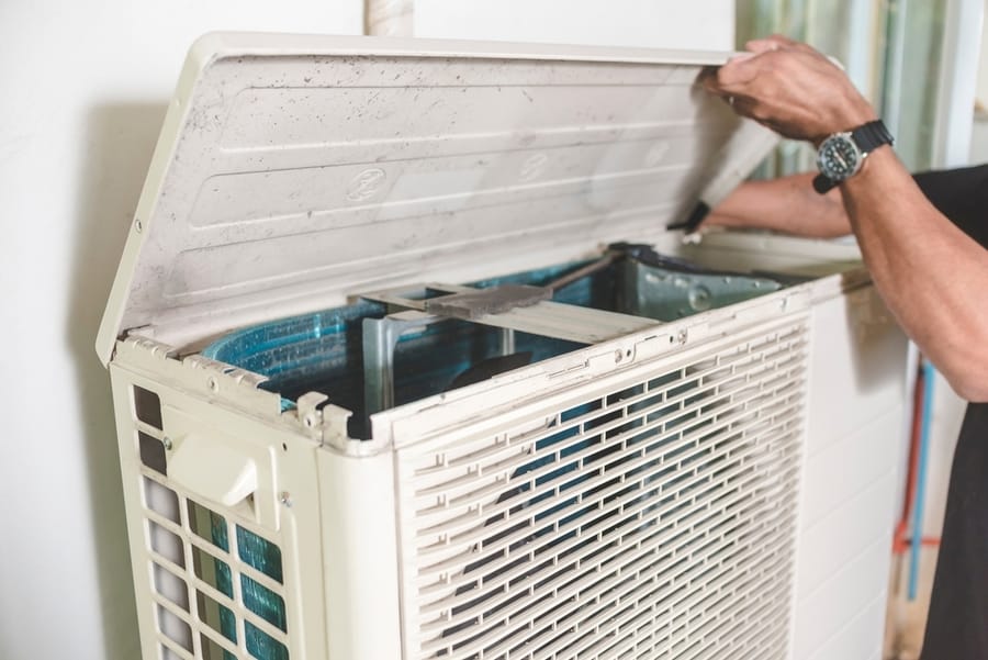A Technician Opens Up The Top Hatch Of The Outdoor Compressor Unit Of A Split Type Air Conditioner. Repair Or Maintenance Work.