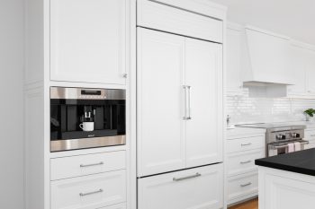 A White, Luxurious Kitchen With Sub-Zero Refrigerator And Built-In Wolf Coffee Maker