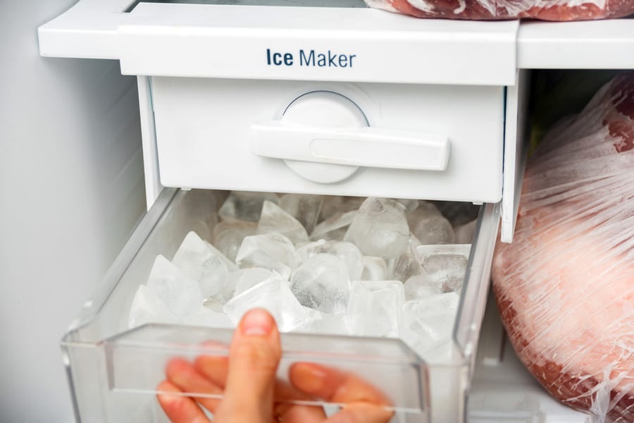 A Woman Opens An Ice Maker Tray In The Freezer To Take Ice Cubes To Cool Drinks.