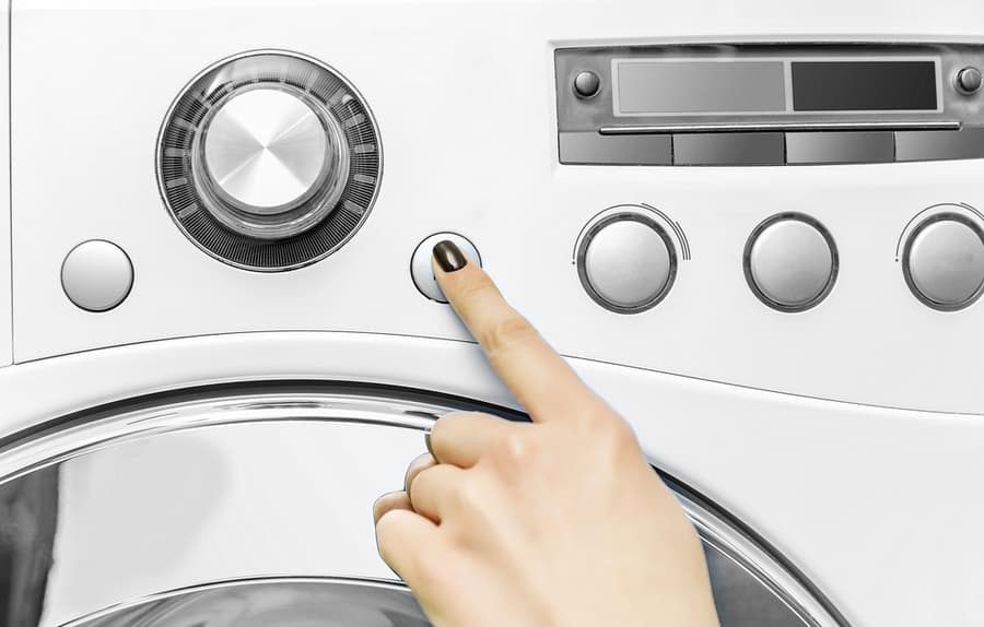 A Woman's Hand Presses A Button On The Washing Machine