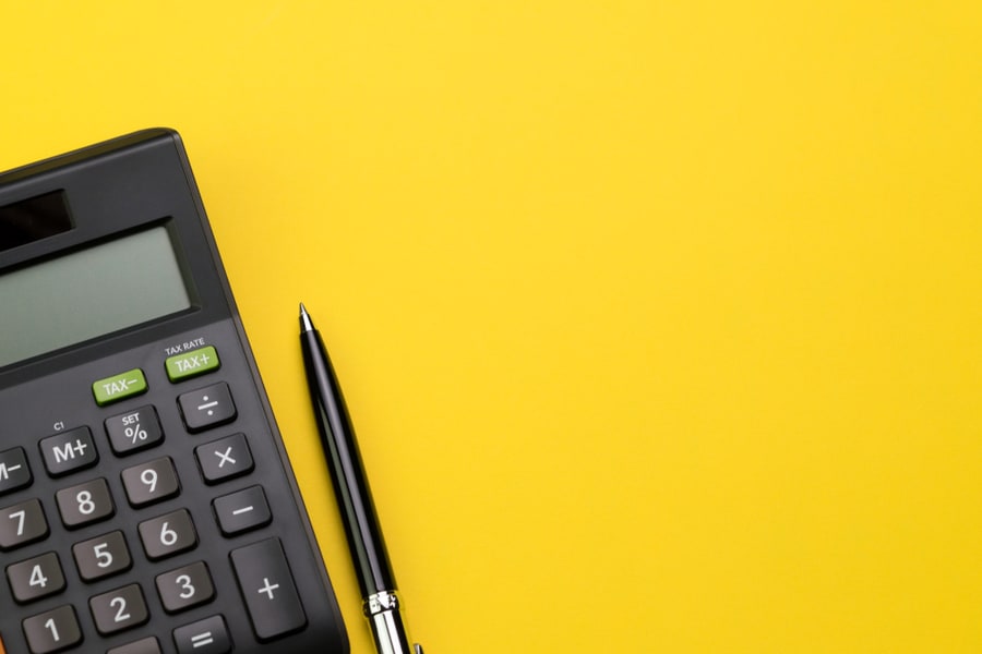 Black Pen With Calculator On Vivid Yellow Background Table