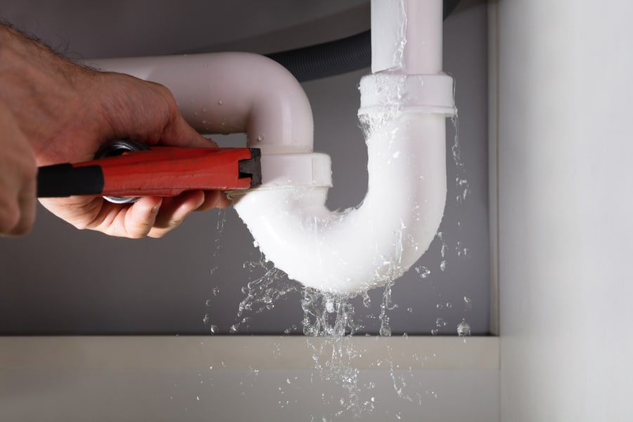 Close-Up Of Male Plumber Fixing White Sink Pipe With Adjustable Wrench
