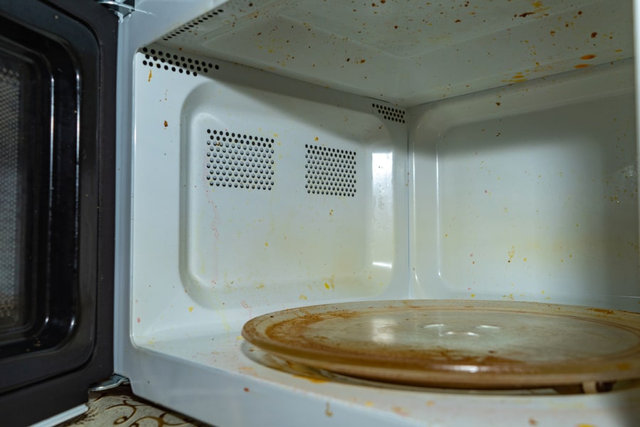 Dirty Microwave Oven. With Burnt Paint On The Walls And Traces Of Grease