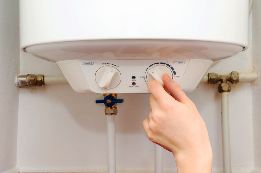 Hand Of A Young Women Setting The Temperature Of The Electric Water Heater.