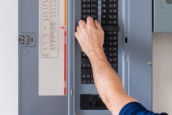 Male Electrician Turning Off Power For Electrical Outlet At Circuit Breaker Box.