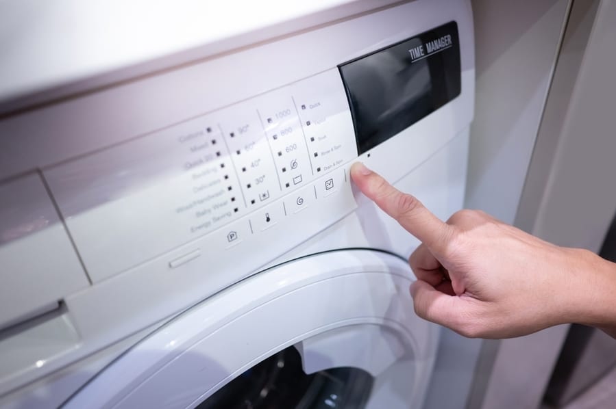 Male Hand Pushing Button Adjusting Mode On White Washing Machine