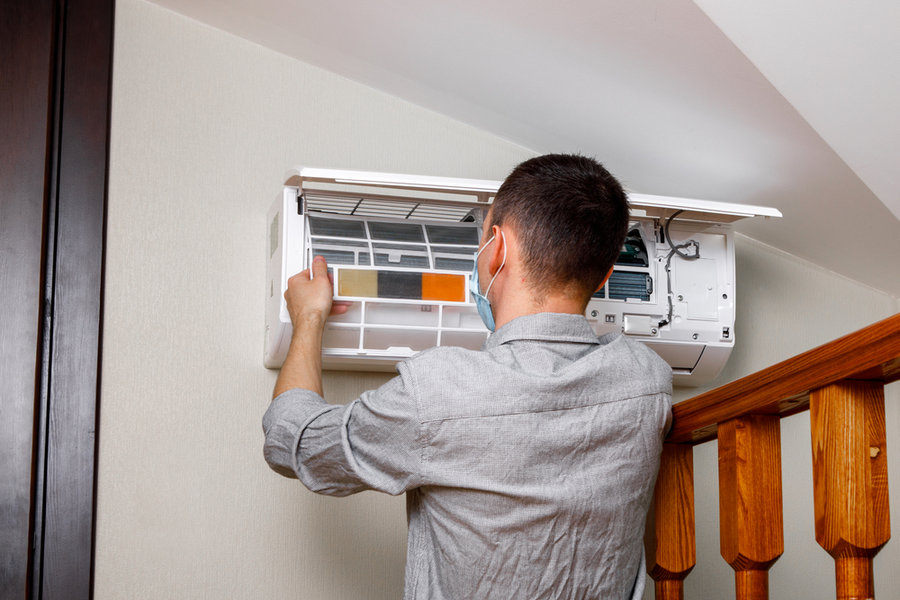 Male Technician Cleaning Air Conditioner Indoors
