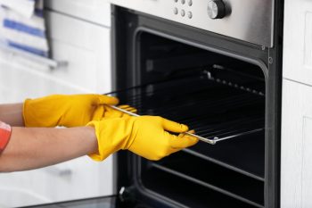 Man Cleaning Oven In Kitchen