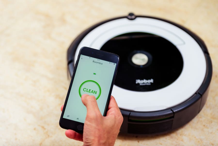 Man Hand Activating The Roomba Irobot Vacuum Cleaner From The Application. Smart Life Concept, Smart City, Smart Home.