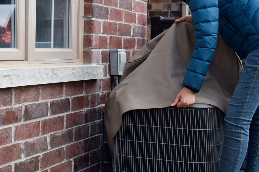 Man Putting Cover On Air Conditioner Unit Outside The House