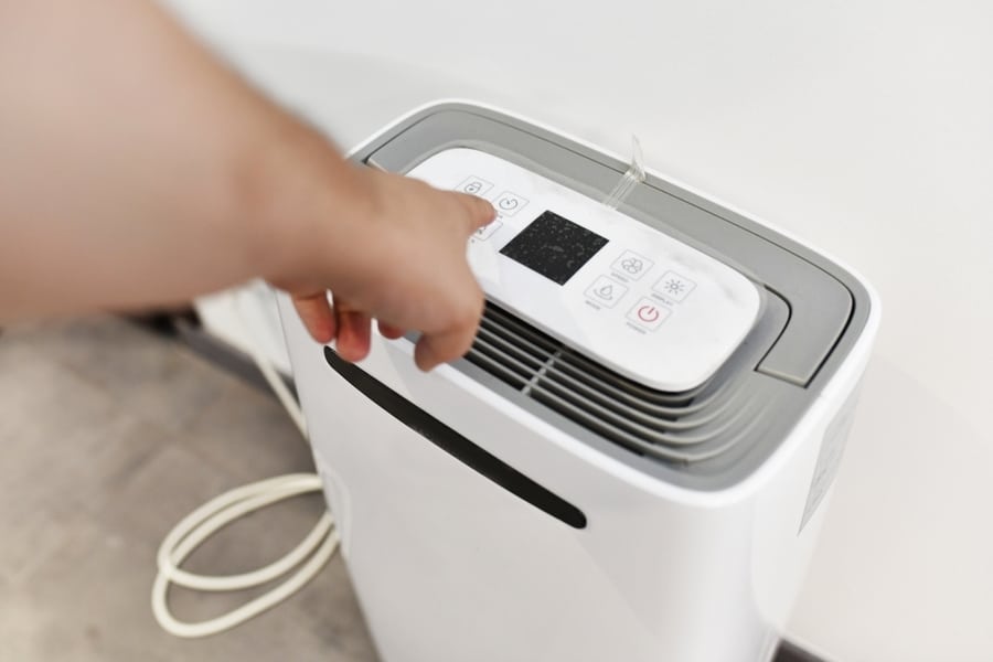 Man's Hand Turning On A Dehumidifier In The Entrance Of A House Or Office. To Prevent Joint Pain