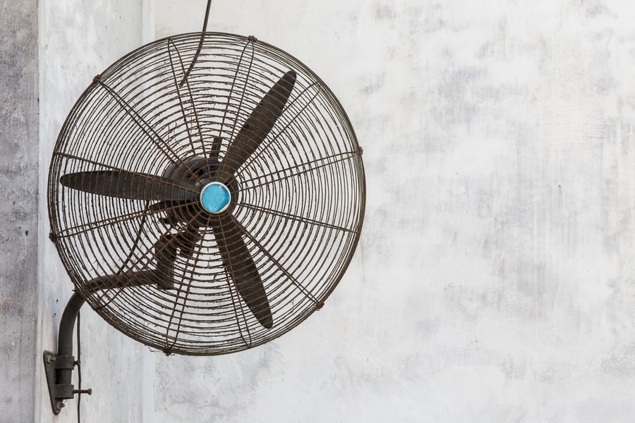 Rusty And Dirty Old Fan Mounted On A Concrete Wall