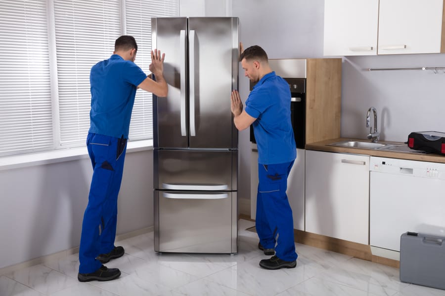 Two Men Positioning The Refrigerator