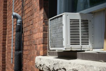 Window Ac Unit Attached To A Brick Walled House