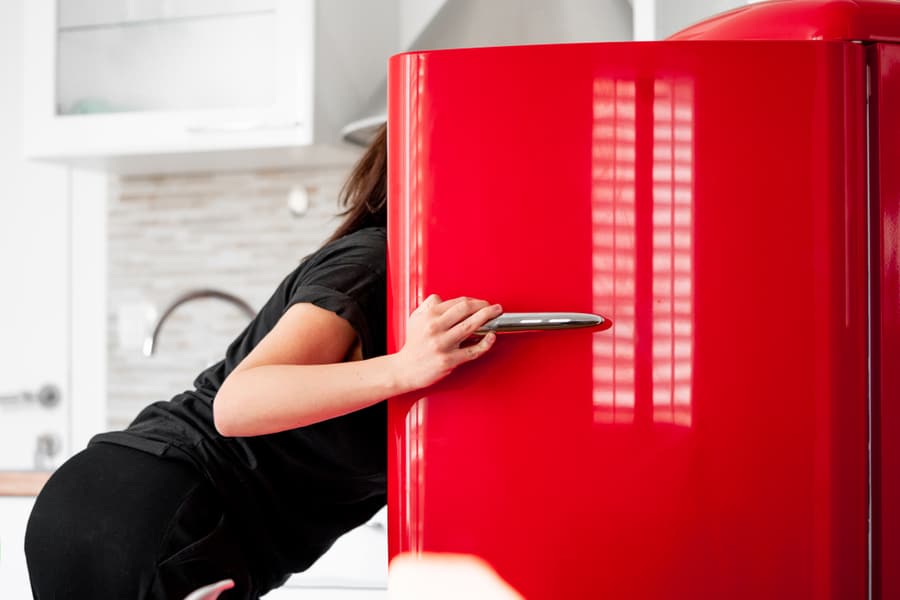 Woman Checkin The Red Refrigerator In Modern Bright Apartments.