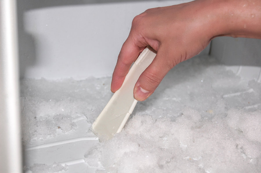 Woman Cleans The Refrigerator With An Ice Scraper, Defrosting Of Freezer.