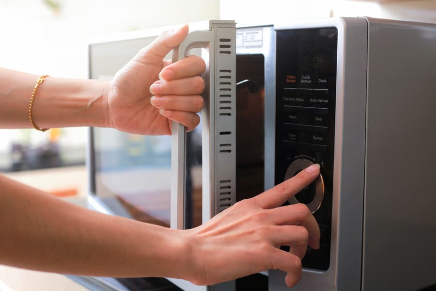 Woman's Hands Closing Microwave Oven Door And Preparing Food In Microwave