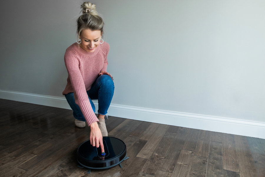 Young Woman Starting Her Robotic Vacuum
