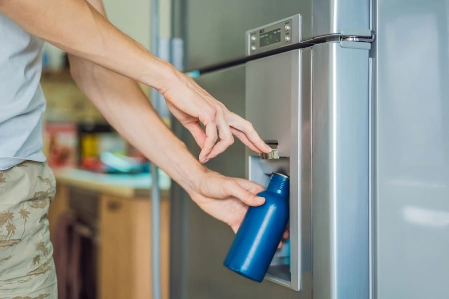 A Man Using The Dispenser Of His Fridge