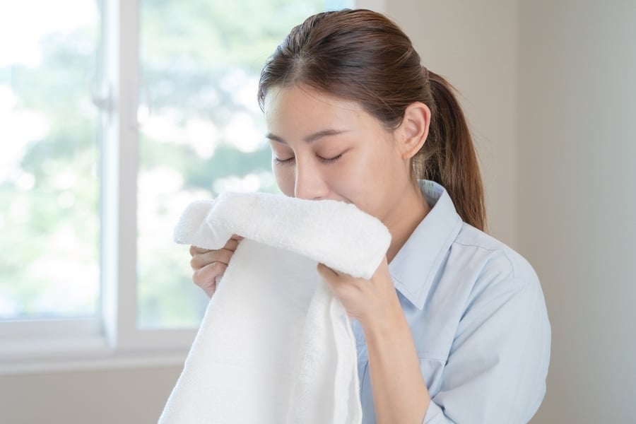 Asian Housewife Smelling Freshness Scent Of Clean Clothes.