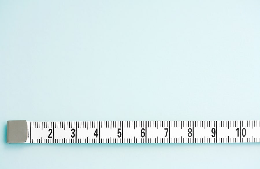Close Up Detail View Of A Measuring Tape Stretched In A Straight Line Isolated On A Clean Blue Background.