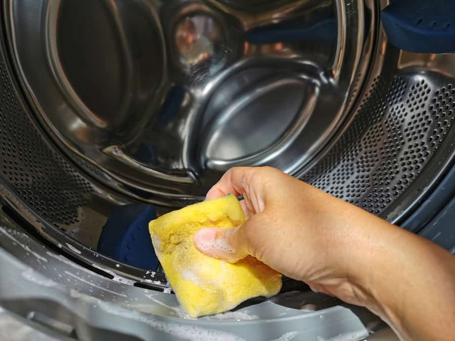 Close Up Hand Use The Spong Cleaning Inside The Washer Drum's Front-Loading Washing Machine