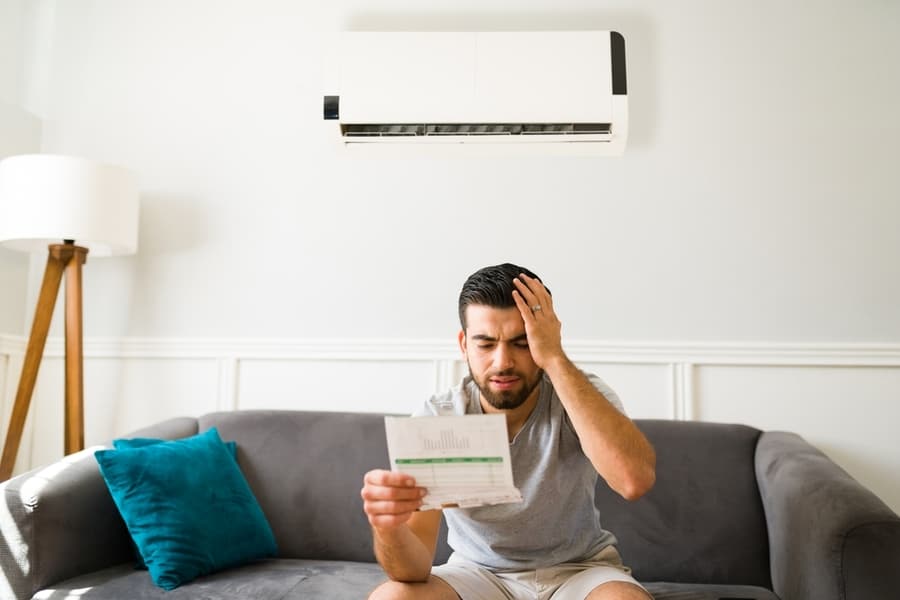 Expensive Bills. Stressed Latin Man Looking At The High Electricity Bill Because Of The Air Conditioning Unit